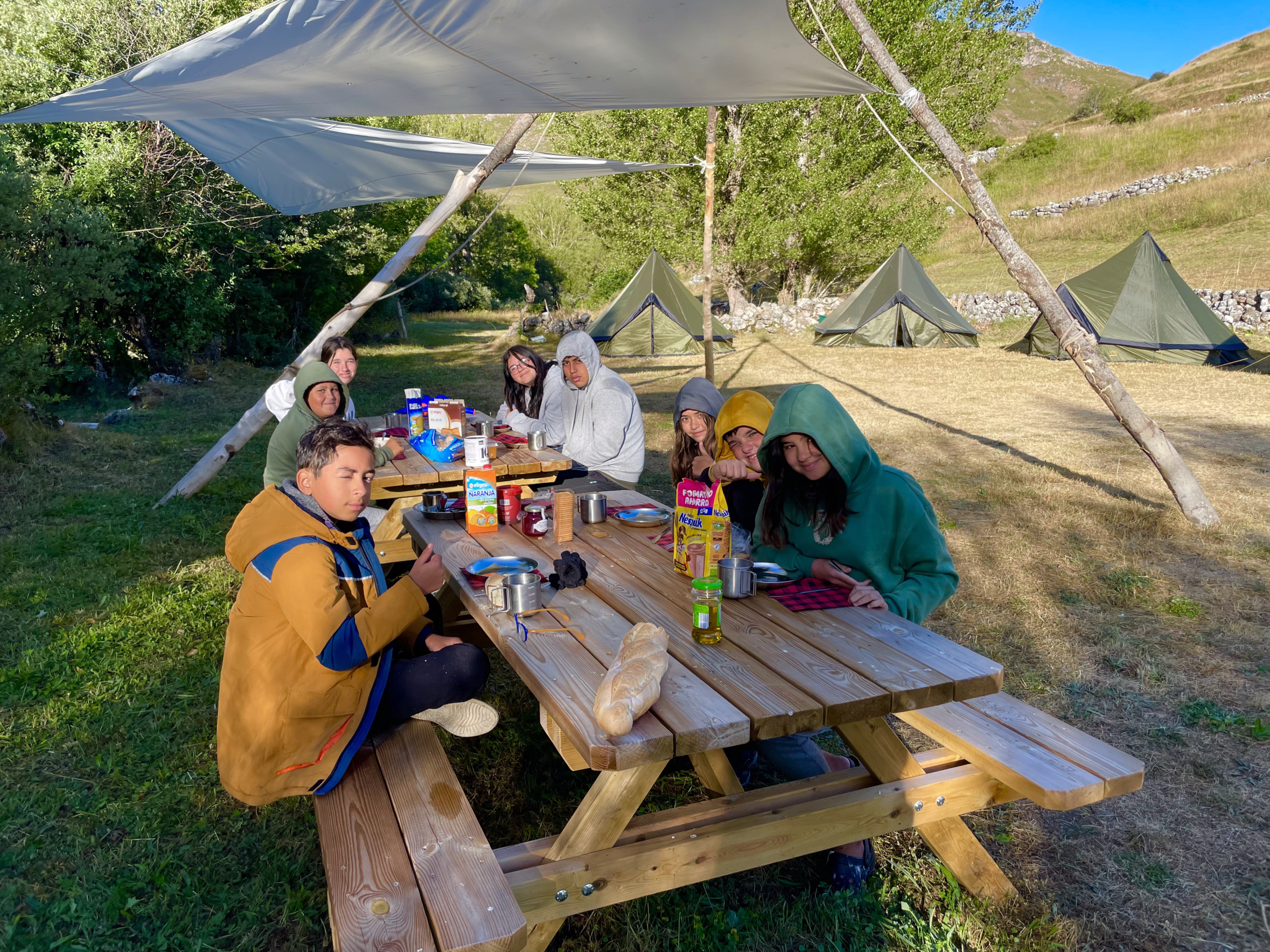 Grupo de jóvenes comiendo entorno a la mesa
